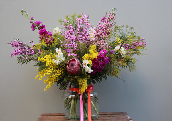 My Girl (A bright, scented bouquet of mimosa, genista, stocks, narcissi and protea in bright yellows and pinks.)