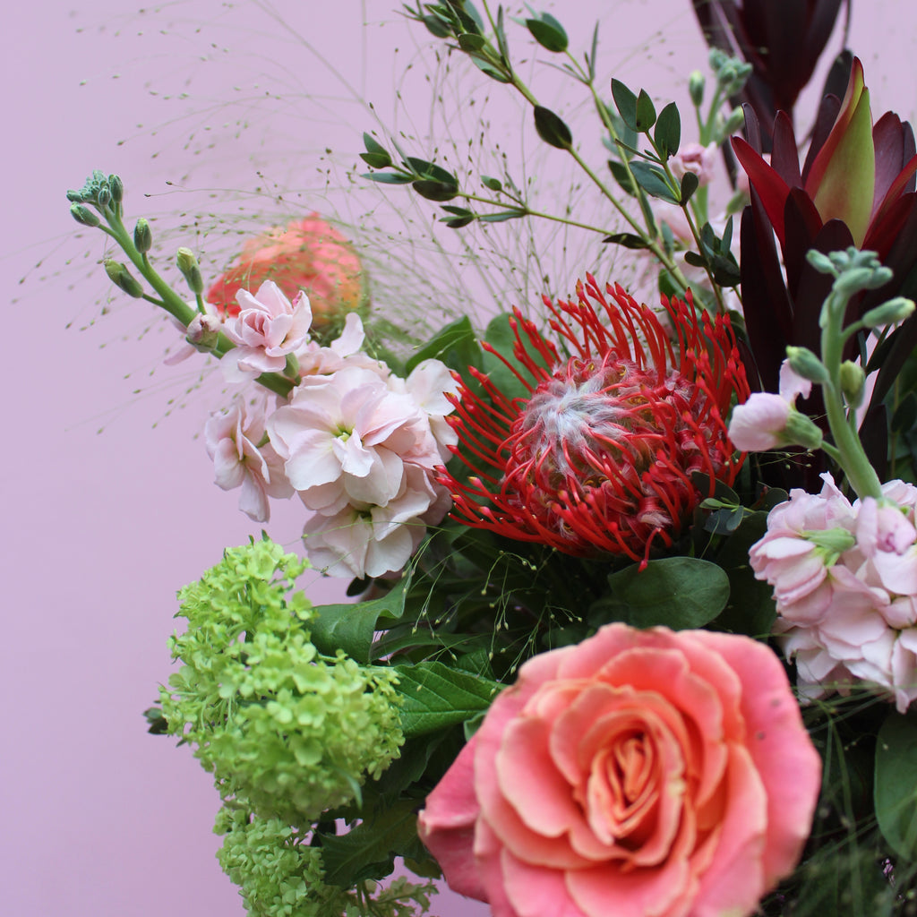 Notting Hill (Cosy winter vibes with this bouquet in reds, peaches, lime green and coral including mixed roses, stocks, pin cushions and viburnum)