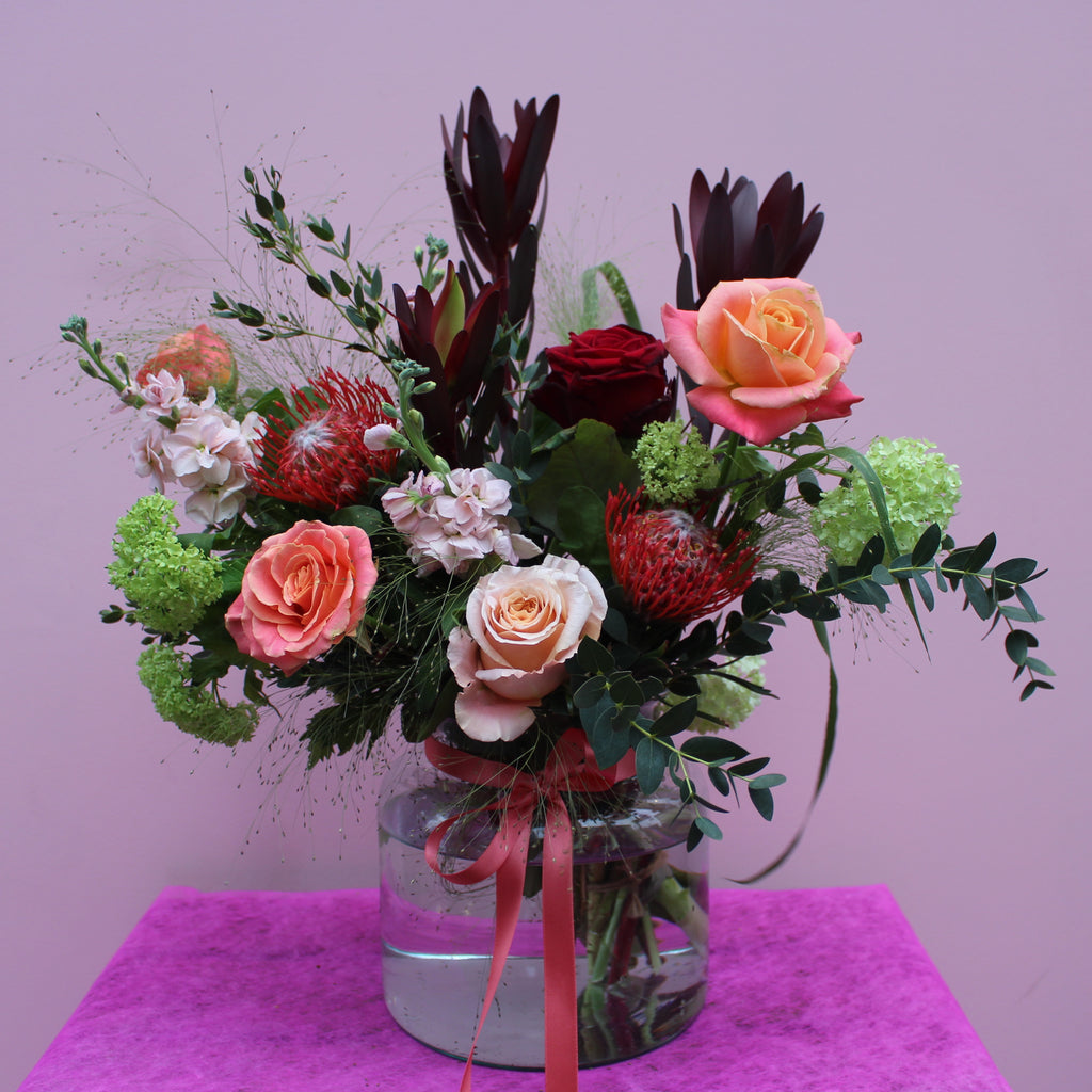 Notting Hill (Cosy winter vibes with this bouquet in reds, peaches, lime green and coral including mixed roses, stocks, pin cushions and viburnum)